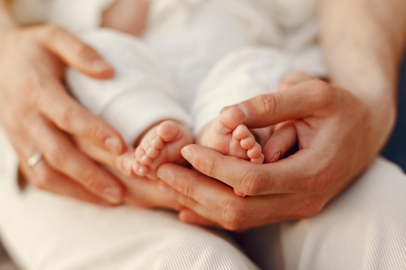 Manos de una madre y un padre sosteniendo los pies de su bebé recién nacido