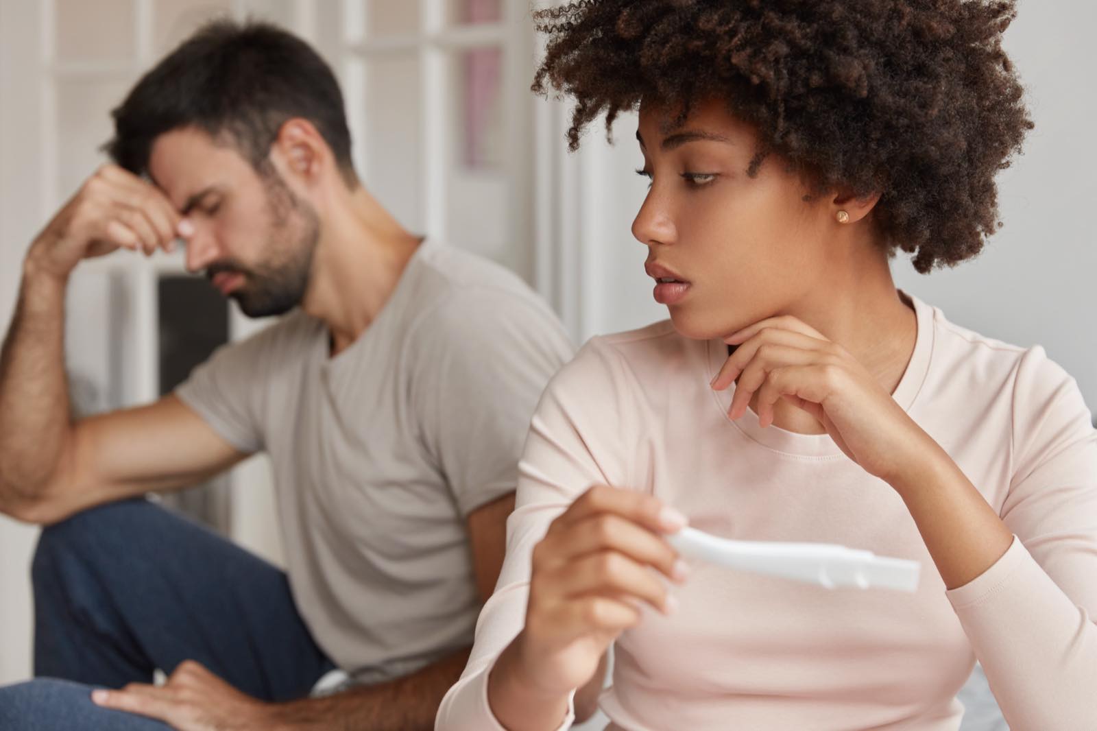 Worried couple at home while she looks at a pregnancy test
