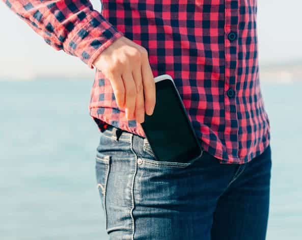 hombre joven guardando su celular en el bolsillo del pantalón