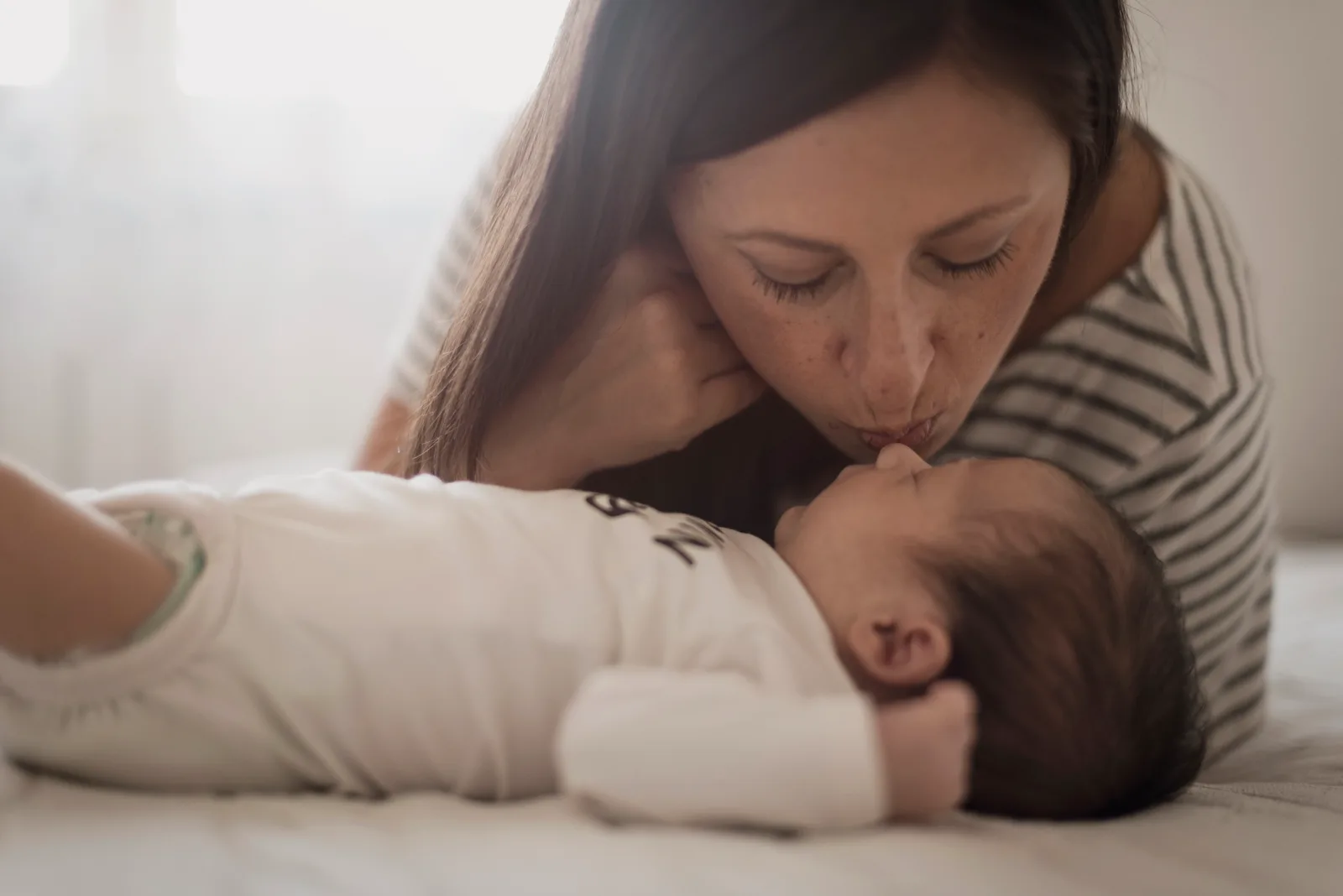 Mujer cargando a sus bebés con amor, sonriendo a cámara