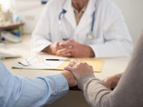 especialista-en-fertilidad-y-ginecologo-pareja-dandose-la-mano-en-consultorio-con-especialista-en-fertilidad